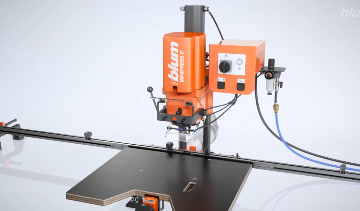Orange Blum MiniPress mounted on a linear rail above a black worktable.